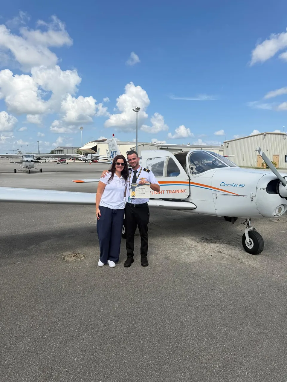 Nuevo piloto con su certificado frente a un Piper Cherokee 140 de AeroService